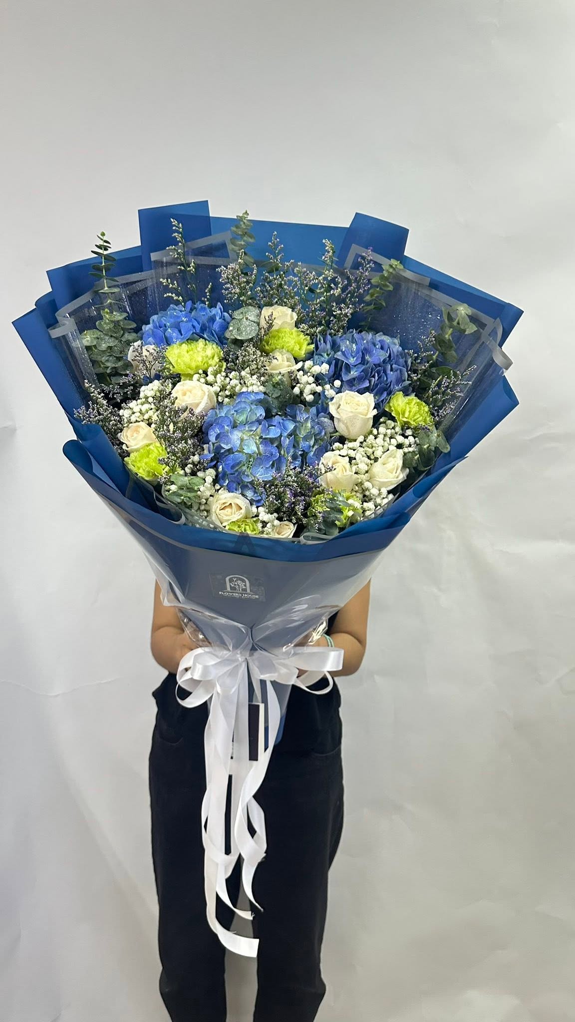 Blue hydrangea, white roses and green carnations wrapped in blue paper